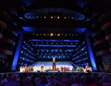 People performing on a large dark indoor stage.