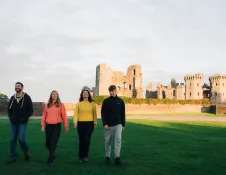 man, woman and two teenagers walking with castle in background.