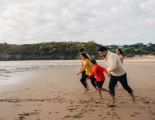 family running on sandy beach.