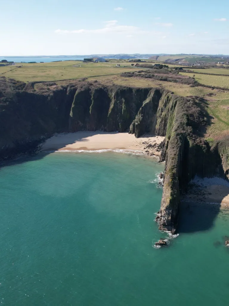 Cildraethau tywodlyd bach rhwng clogwyni garw uchel.