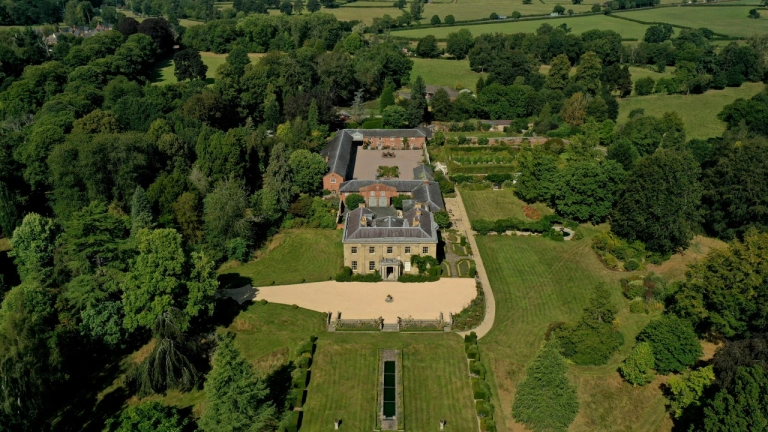 An aerial shot of a manor house and garden surrounded by countryside.