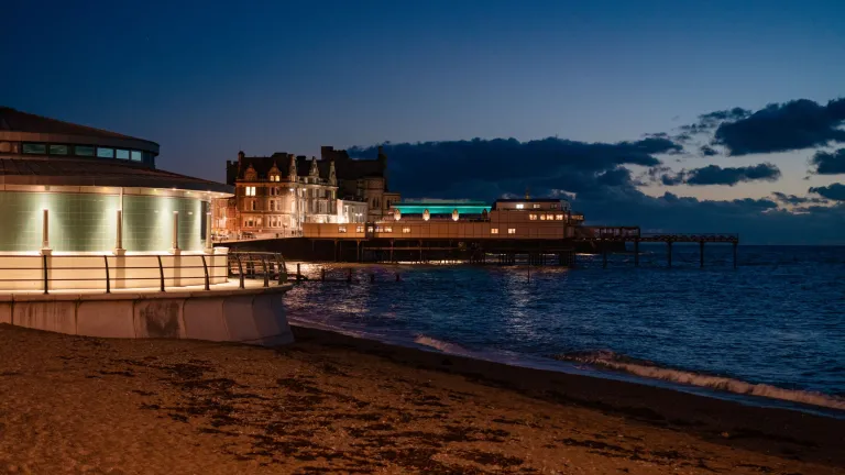 Glan môr Aberystwyth yn y nos gyda'r pier wedi goleuo