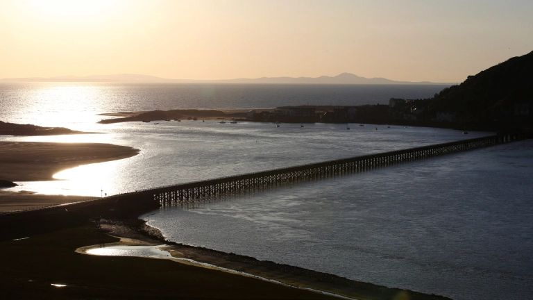 Pont Abermaw wrth iddi fachlud yn edrych draw tuag at y môr