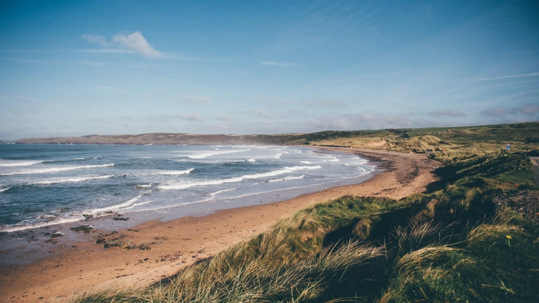 Golygfa o draeth gyda tonnau yn y mor