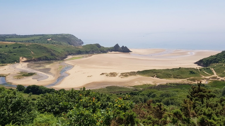  Golygfa o draeth tywodlyd a chlogwyni
