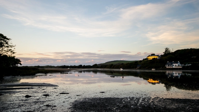 Golygfa yn edrych dros y môr o'r traeth yn y cyfnos