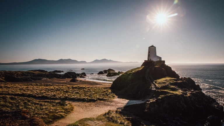 Goleudy Llanddwyn a'r traeth yn haul cryf y gaeaf