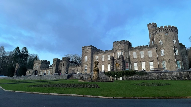 Golygfa flaen o gastell wedi'i amgylchynu gyda glaswellt