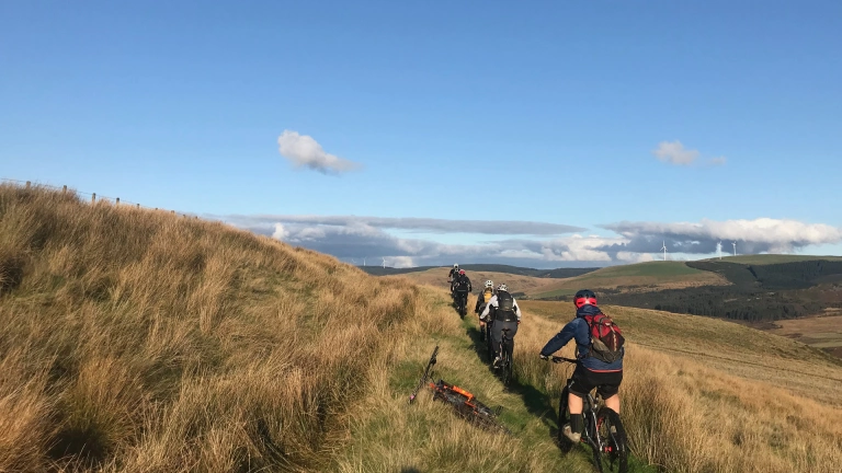 Beicwyr mynydd ar lwybr ar ochr bryn.