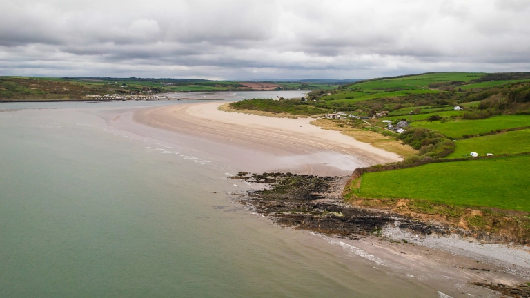 Golygfa o’r awyr o draeth tywod llydan.