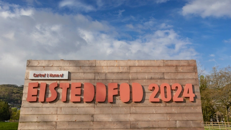Arwydd Eisteddfod 2024 ac awyr las.