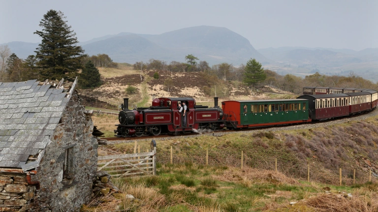 Red and green steam train travelling through the mountains