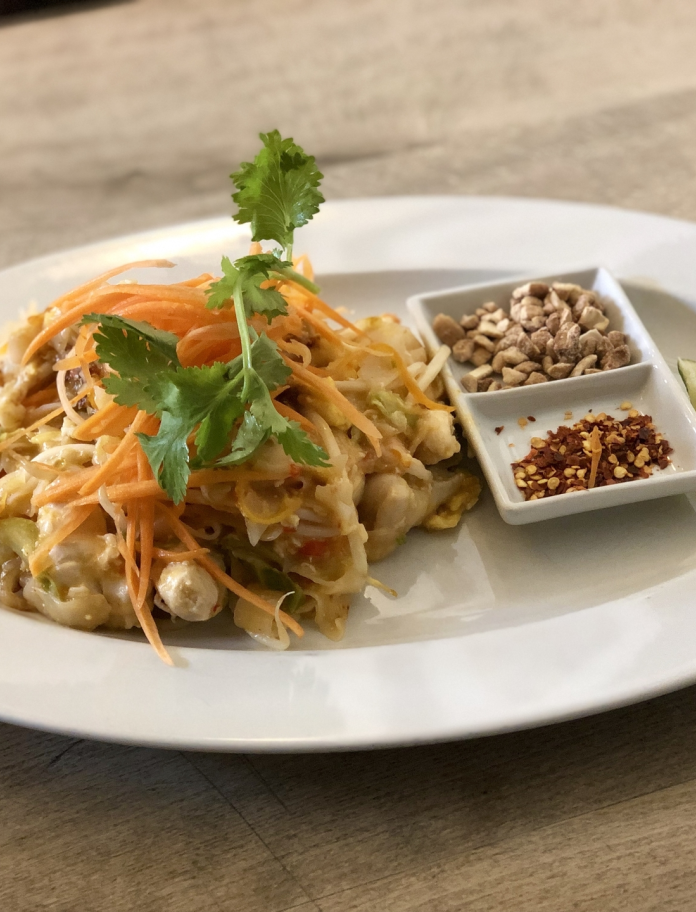 Plataid o fwyd Thai gyda chnau cashiw a naddion tsili ar yr ochr.