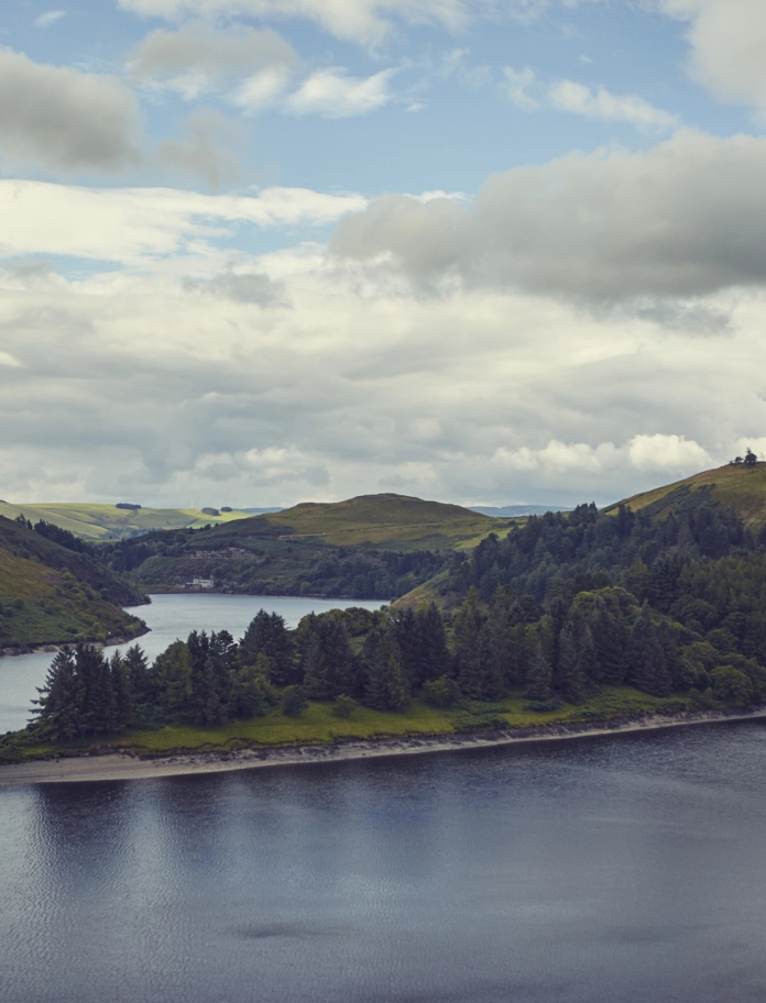 Golygfa o ddyffryn wedi'i amgylchynu gan afon gyda cymylau gwyn yn yr awyr