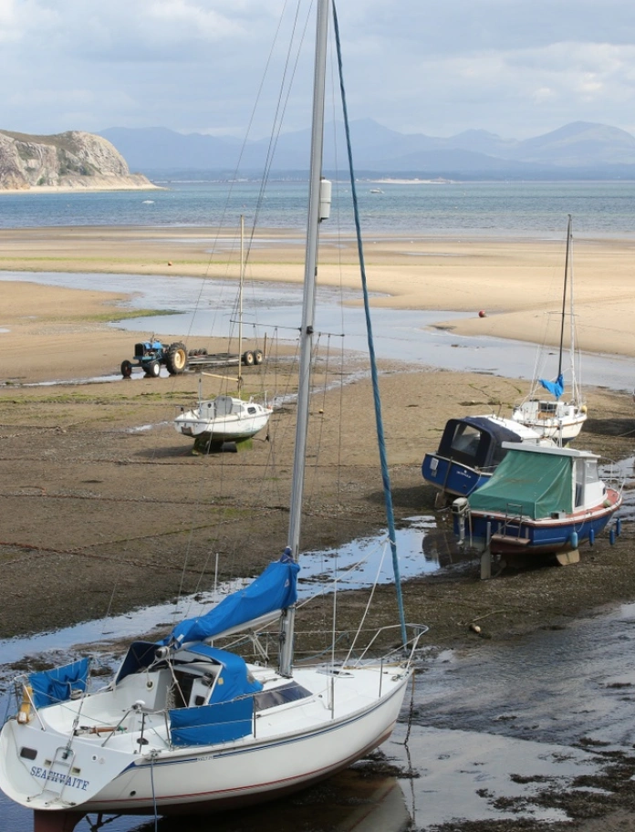 Cychod ar y traeth gyda'r môr yn y cefndir