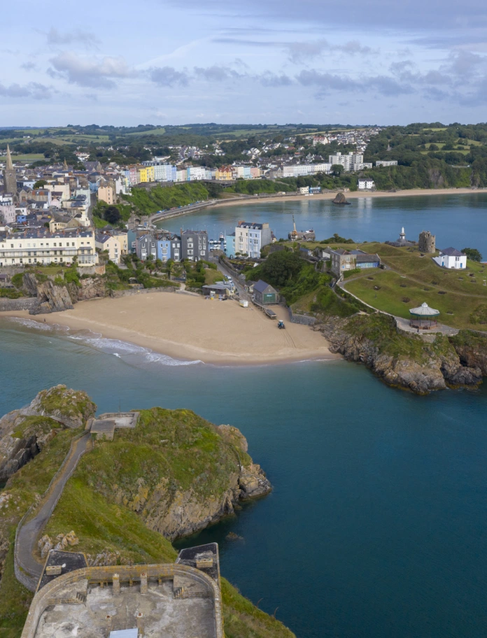 Golygfa o Ddinbych-y-pysgod o'r awyr yn dangos traethau, tref ac ynys.