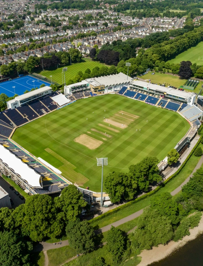 Stadiwm criced ar lan afon oddi uchod.