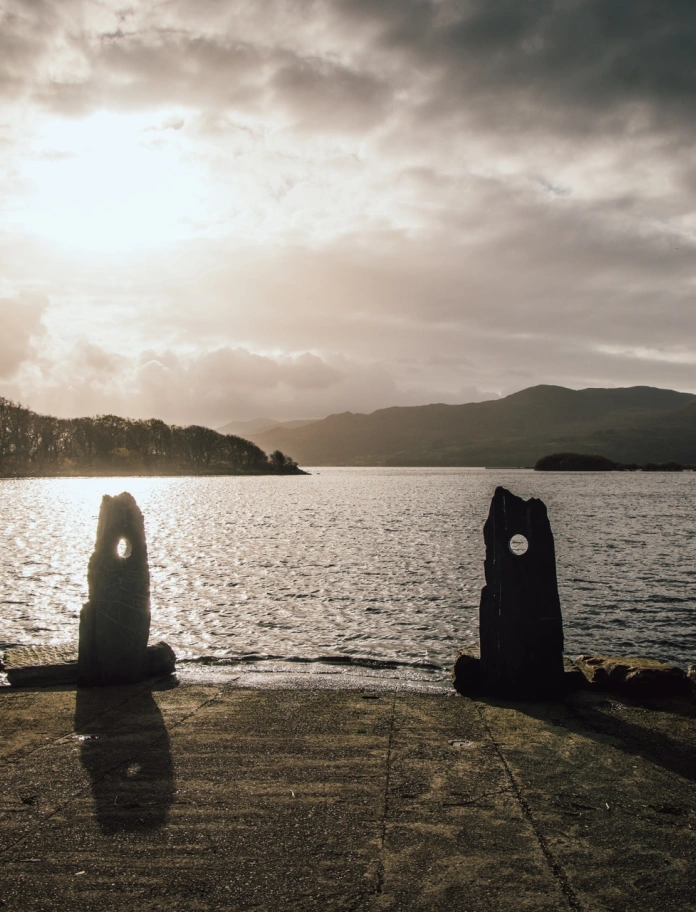 Llyn mewn gwyll, gyda cholofnau ar y lan.