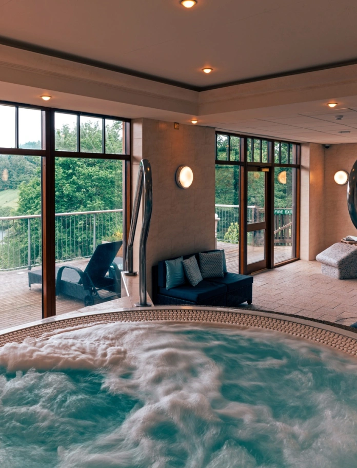 Y tu mewn i sba gyda jacuzzi, cadeiriau ymlacio a golygfeydd dros lyn.