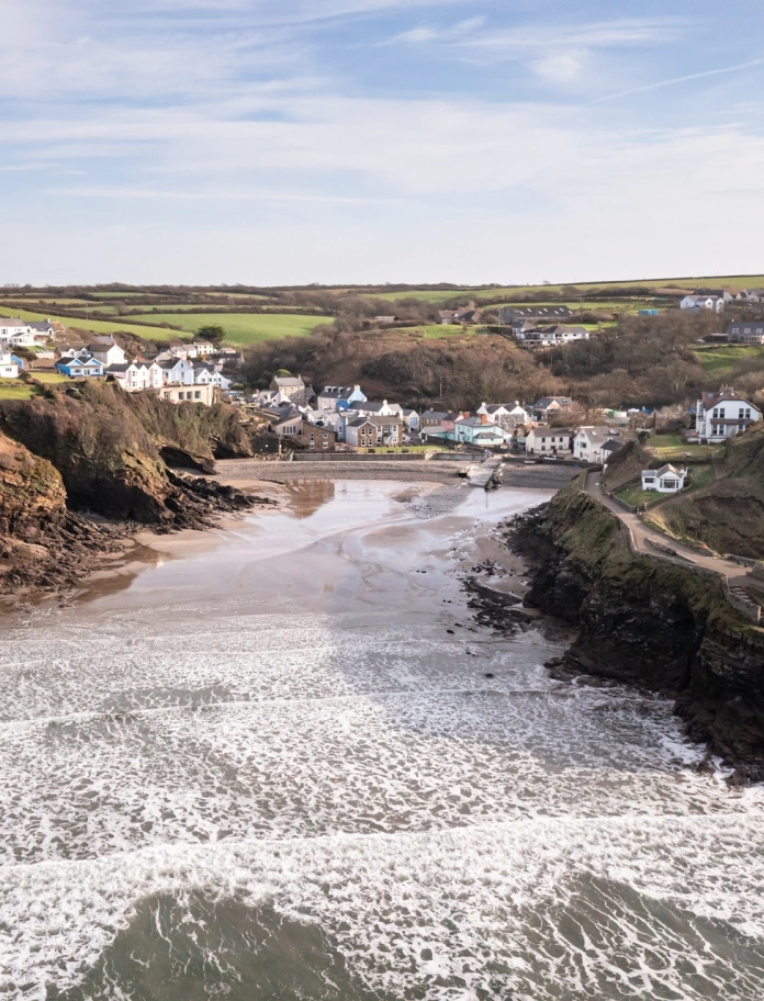 Pentref o amgylch cildraeth tywodlyd ger y môr.