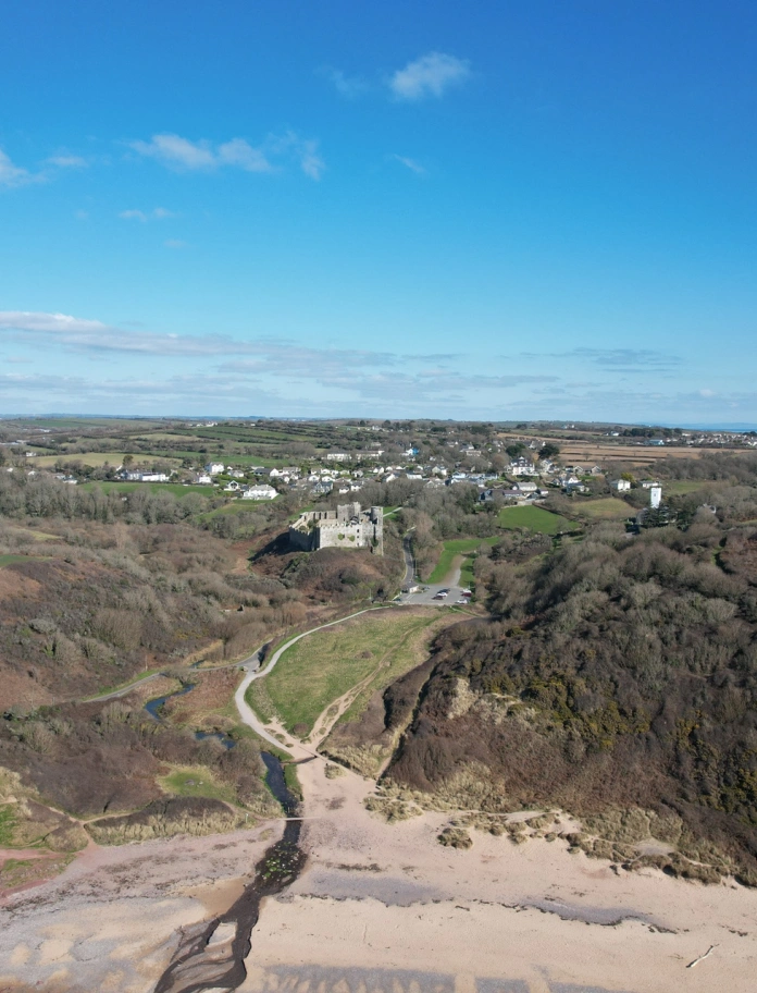Golygfa o draeth mewn cwtch yn edrych tuag at Gastell