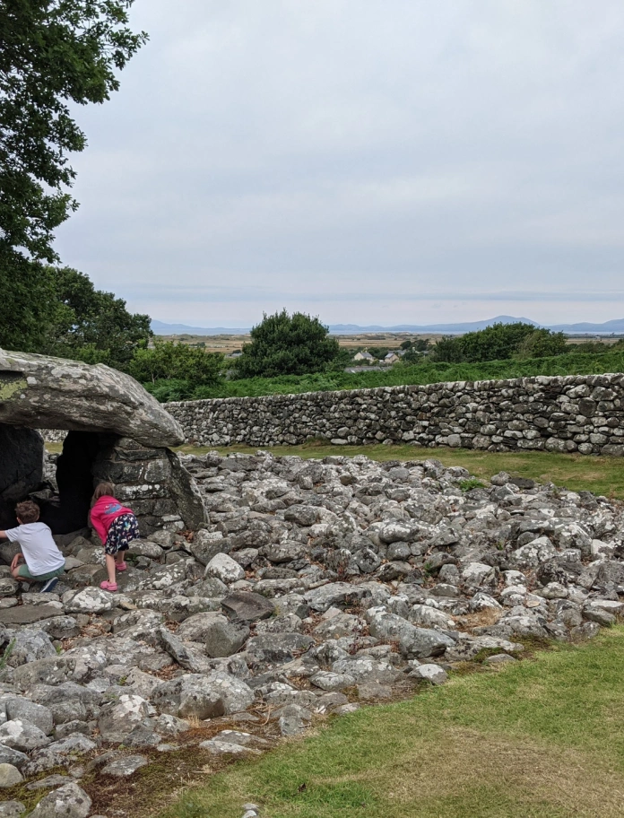 Dau blentyn yn archwilio siambr gladdu gerrig.