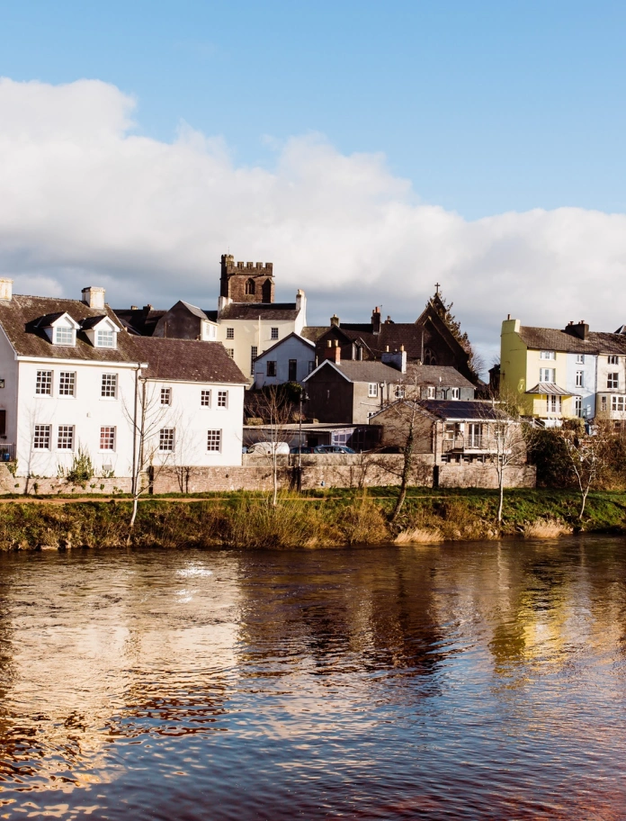 Afon gyda thai ar hyd y lan ac Eglwys Gadeiriol Aberhonddu yn y pellter