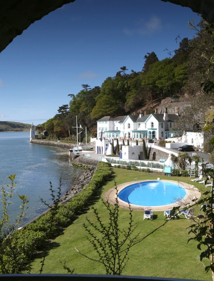 Gwesty Portmeirion a'r pwll nofio awyr agored ar ddiwrnod heulog.