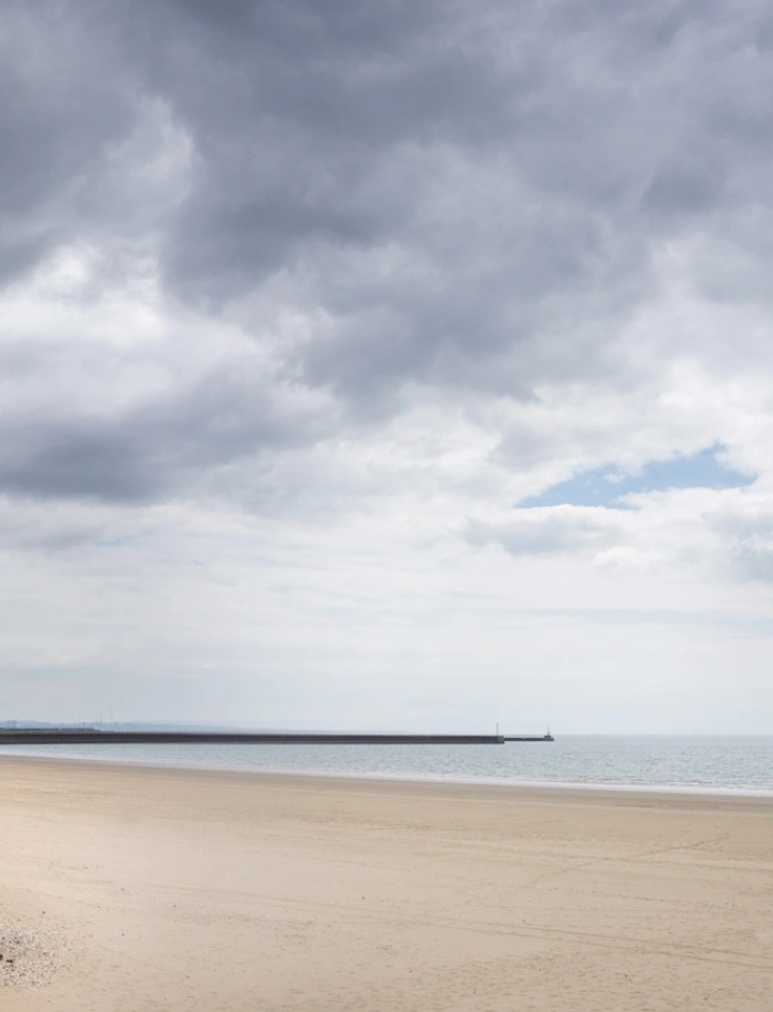 Traeth gwastad, tywodlyd ger promenâd.