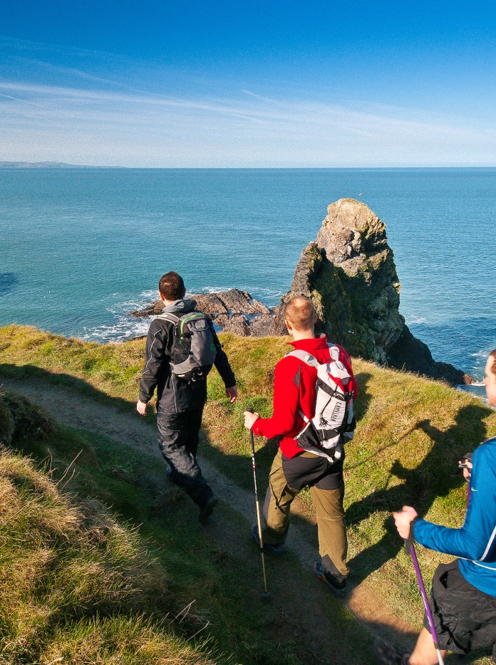 Three male walkers on Wales Coast Path, Pembrokeshire, West Wales