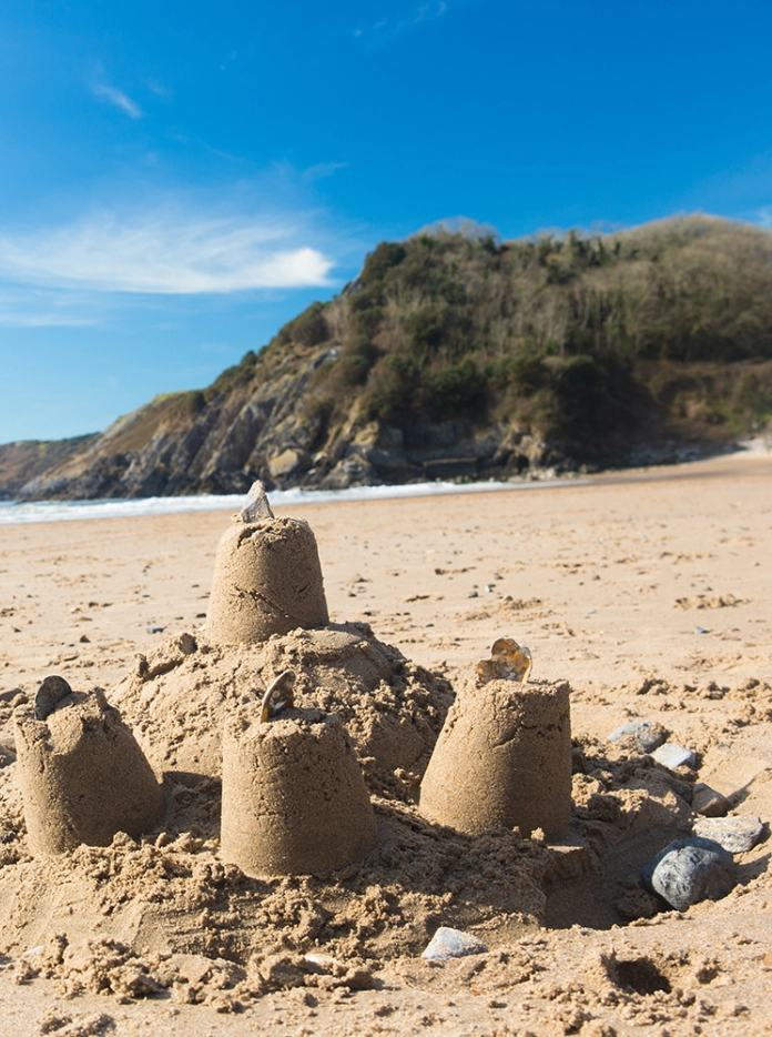 Cestyll tywod ar y traeth gyda'r môr a'r awyr yn y pellter.
