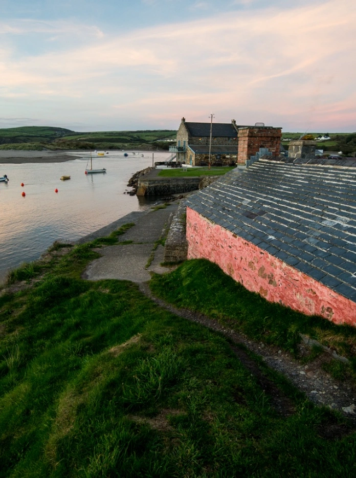 Golygfa o adeiladau sy'n edrych dros yr arfordir gyda cychod yn y dŵr