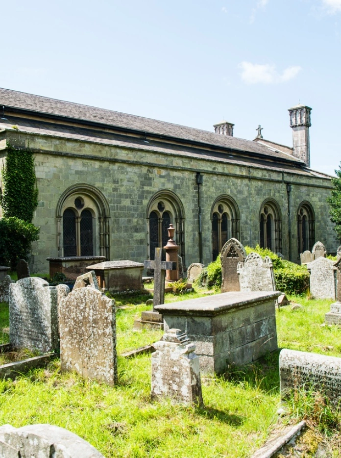Abaty Margam o'r tu allan gyda beddau o'i cwmpas