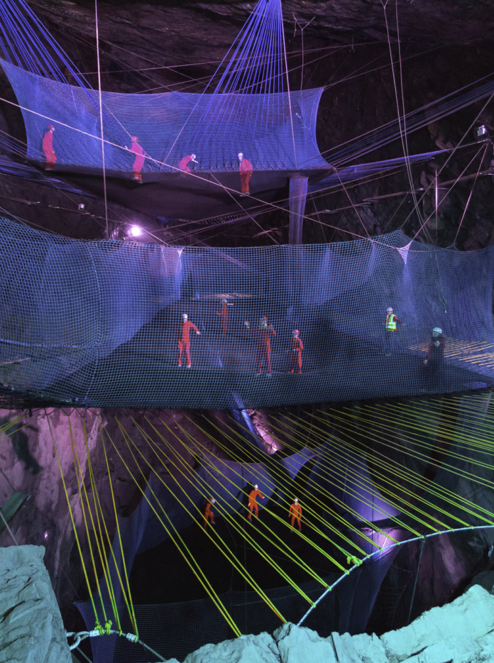 Pobl yn bownsio ar rwydi ar ffurf trampolîn mewn ogof lechi danddaearol