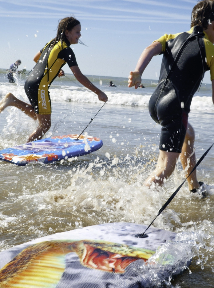 Children body boarding on a beach.