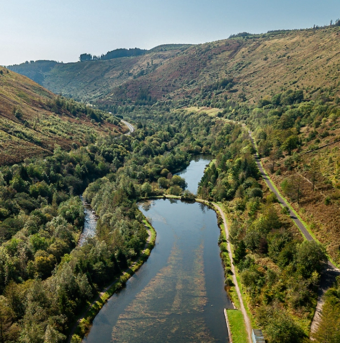 Drone view of lake and green valley and trails in Afan Forest Park.