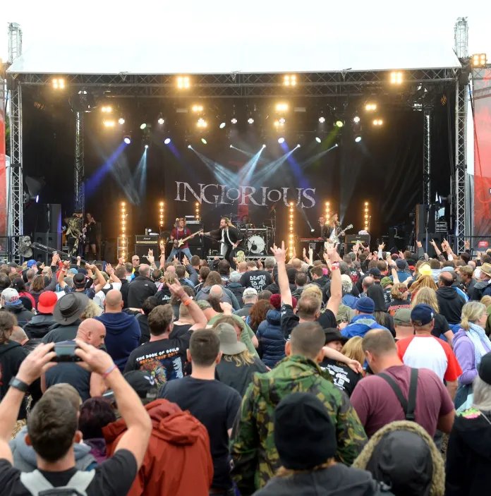 A crowd of music fans enjoying a rock band on stage.
