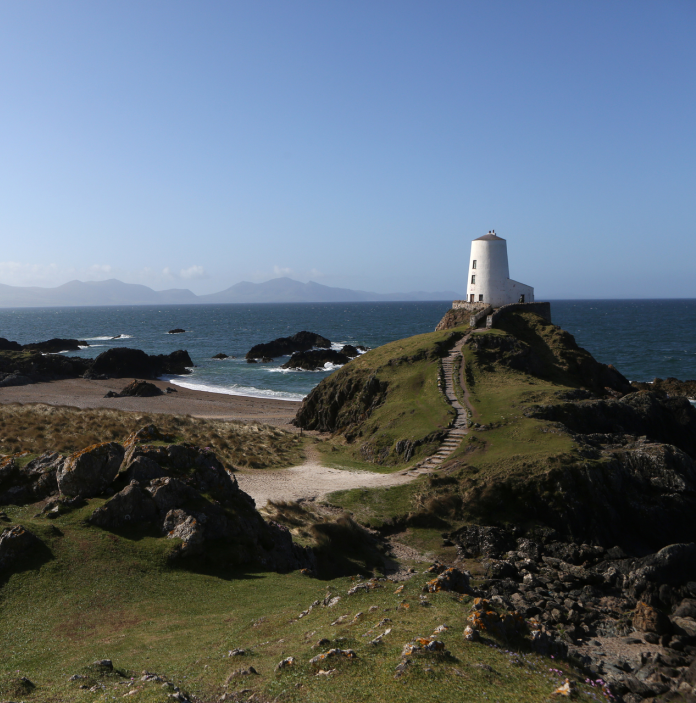 Llun o'r traeth a'r goleudy ar Ynys Llanddwyn