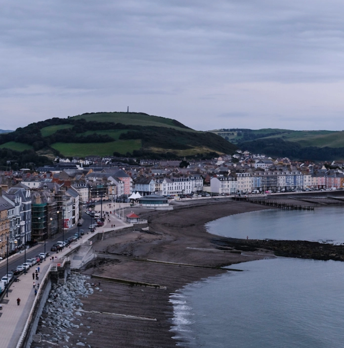 Glan môr, prom a phier Aberystwyth, gyda Phen Dinas yn y pellter