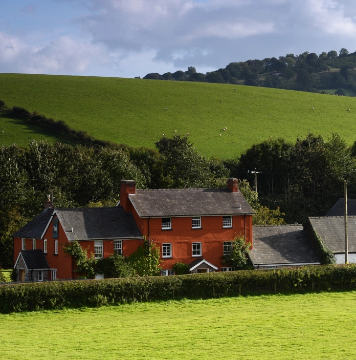 Llun o fwyty gyda waliau coch, a bryniau gwyrdd yn y cefndir