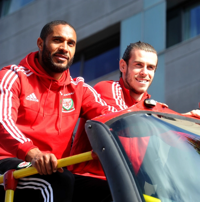 Llun o Ashley Williams, Gareth Bale a Chris Gunter yn eistedd ar fws heb do