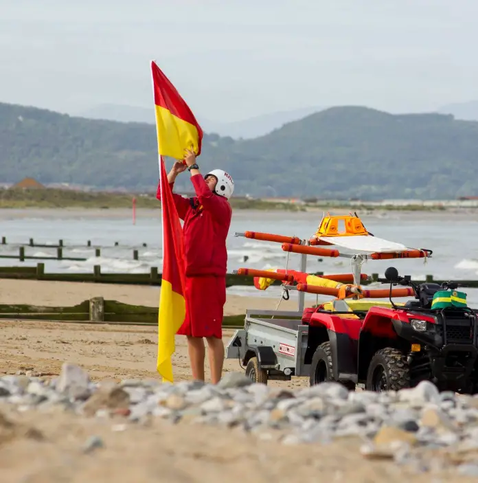 Achubwr bywyd yn gosod baneri coch a melyn ar draeth y Rhyl