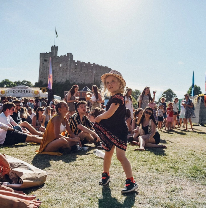 Merch fach yn dawnsio yn Tafwyl, gyda Chastell Caerdydd yn y cefndir