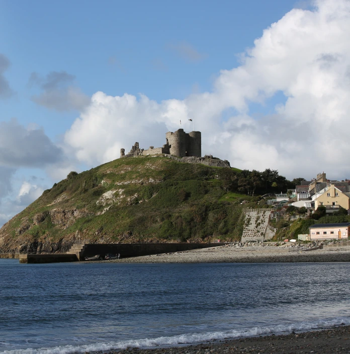 Llun o gastell ar ben bryn gyda'r môr yn y tu blaen