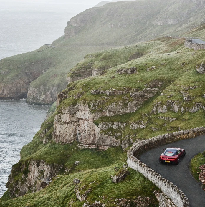 Car yn gyrru ar hyd ffordd droellog gyda'r môr ar yr ochr chwith