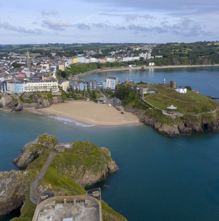 Golygfa o Ddinbych-y-pysgod o'r awyr yn dangos traethau, tref ac ynys.