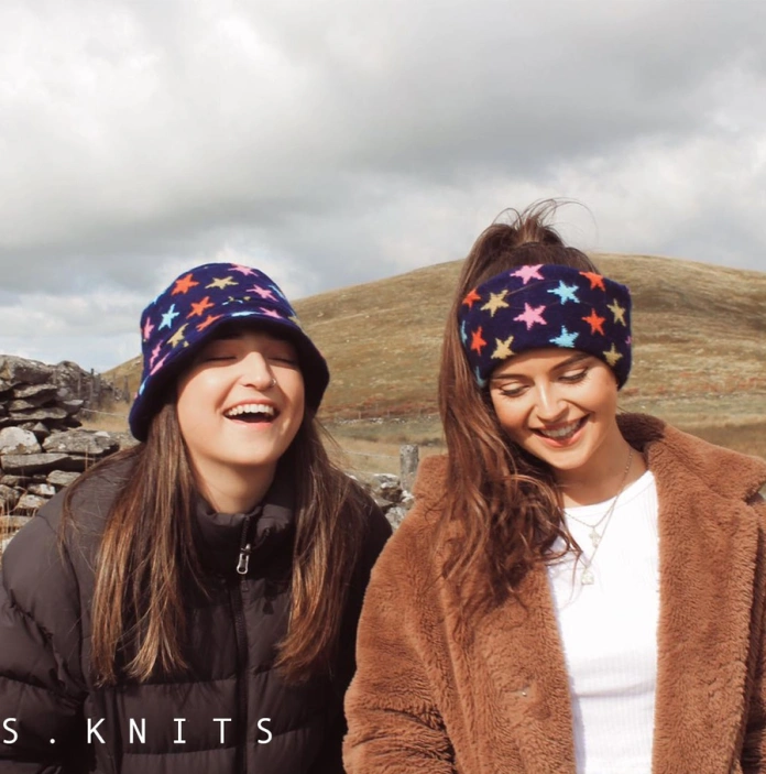 Dwy ferch yn modelu het a sgarff o Gasgliad Alis Knit