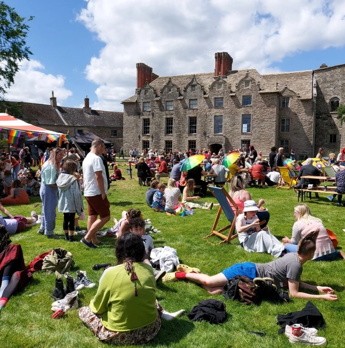 pobl yn eistedd ar lawnt o flaen castell.