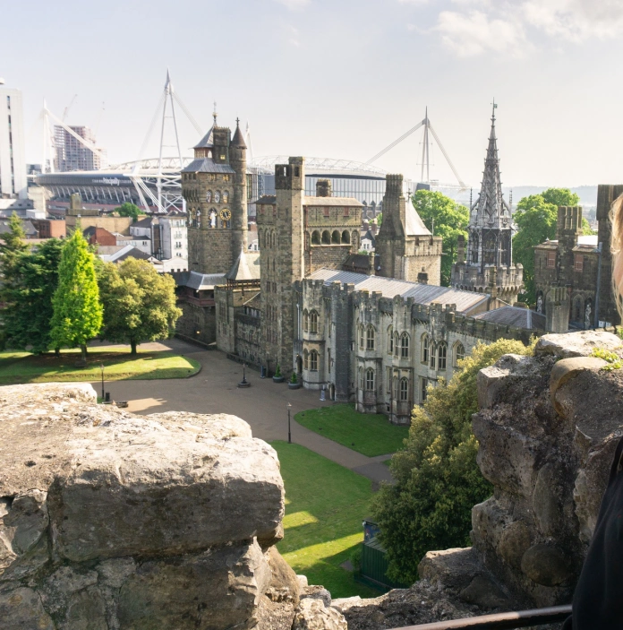 view of inner castle and modern buildings from keep with woman looking at the view.