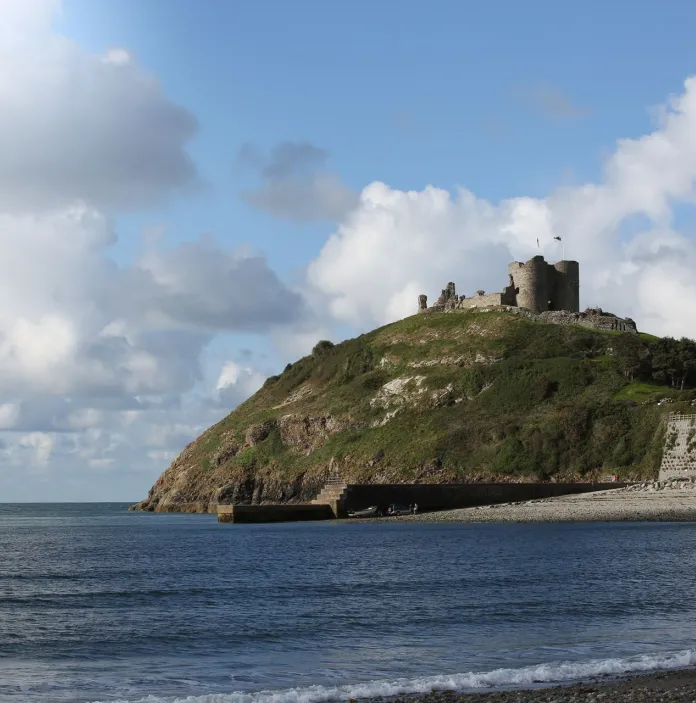 Llun o gastell ar ben bryn gyda'r môr yn y tu blaen